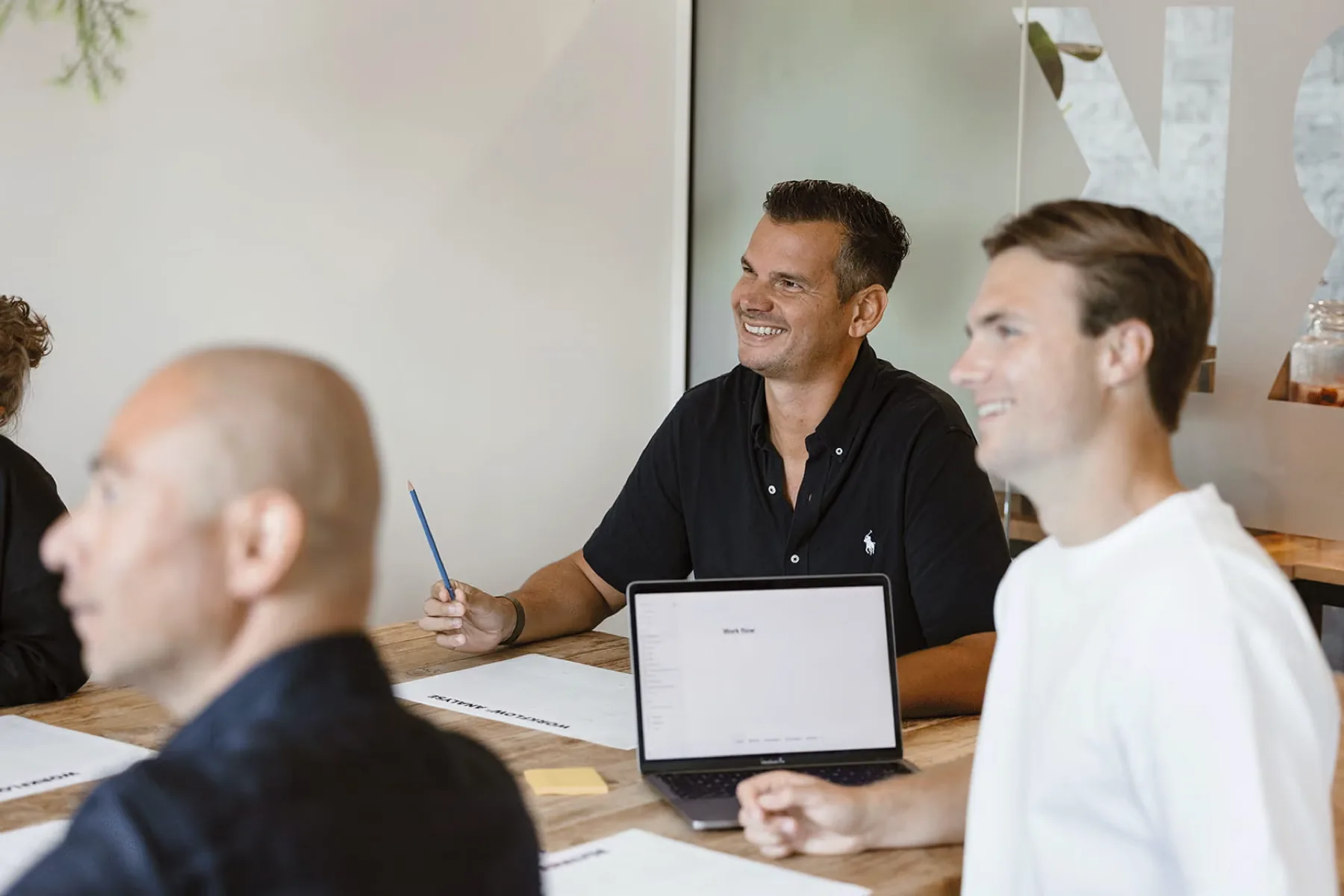 Drie collega's van Huray overleggen aan tafel met een laptop tussen zich in.