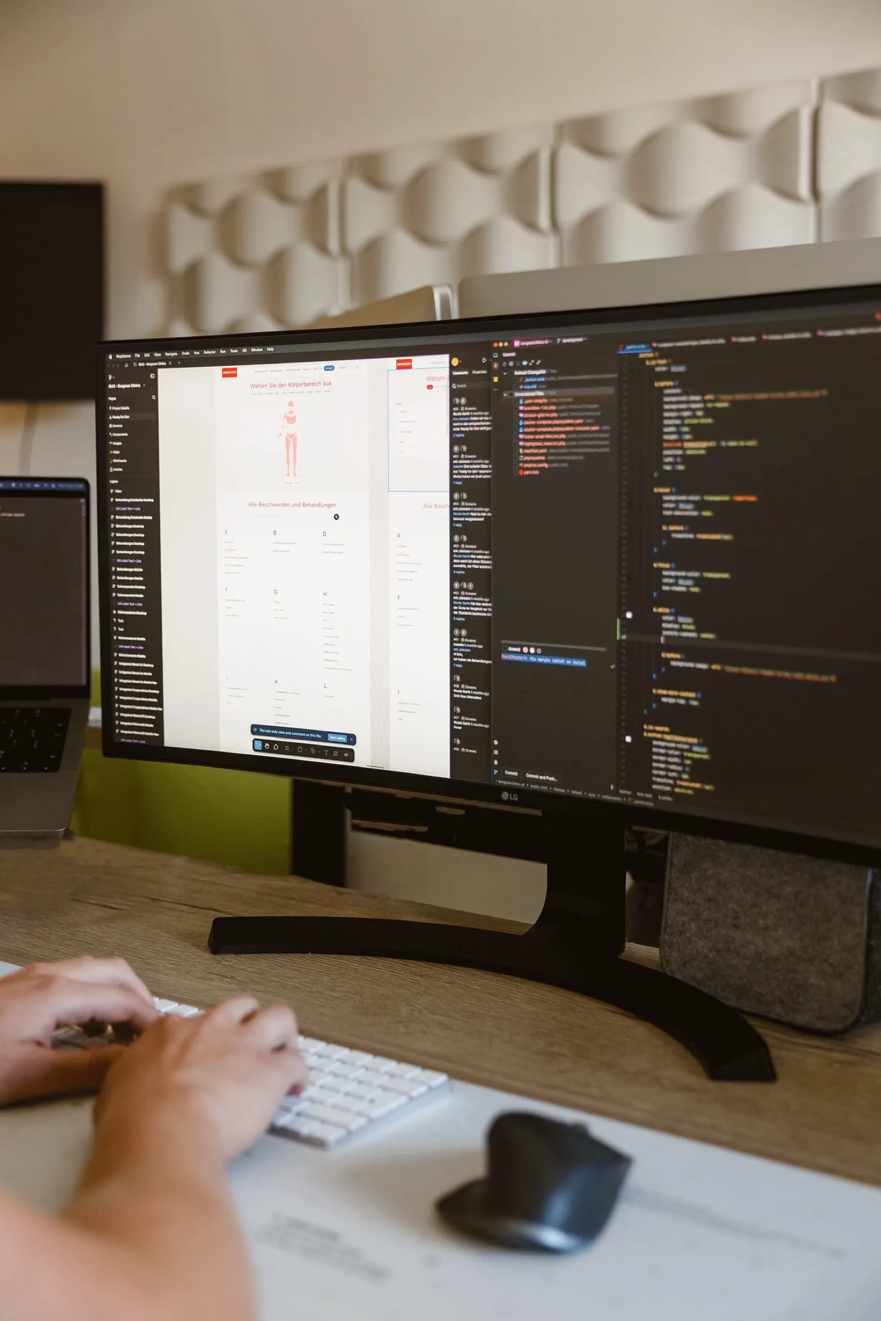Een breed scherm met code en een ontwerpinterface, met iemand aan het toetsenbord.